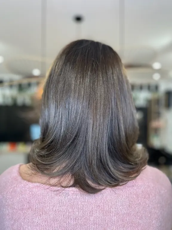 Coloration châtain cendré sur cheveux mi-longs, pointes brushées, réalisée au salon XOXO COIFFURE