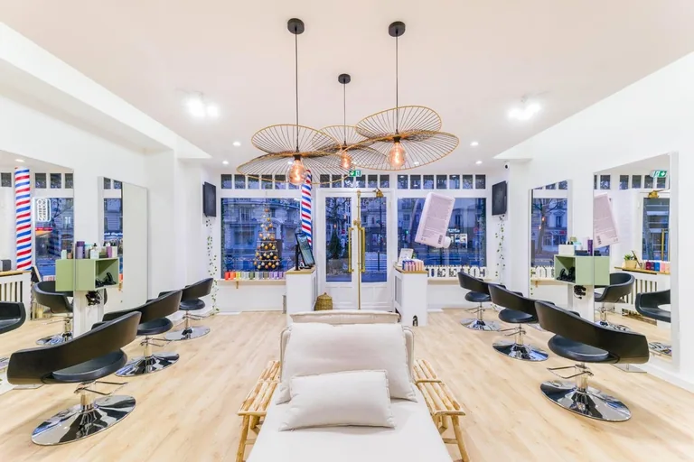 Intérieur du salon XOXO COIFFURE Paris 6e — postes de coiffage sous de grandes suspensions